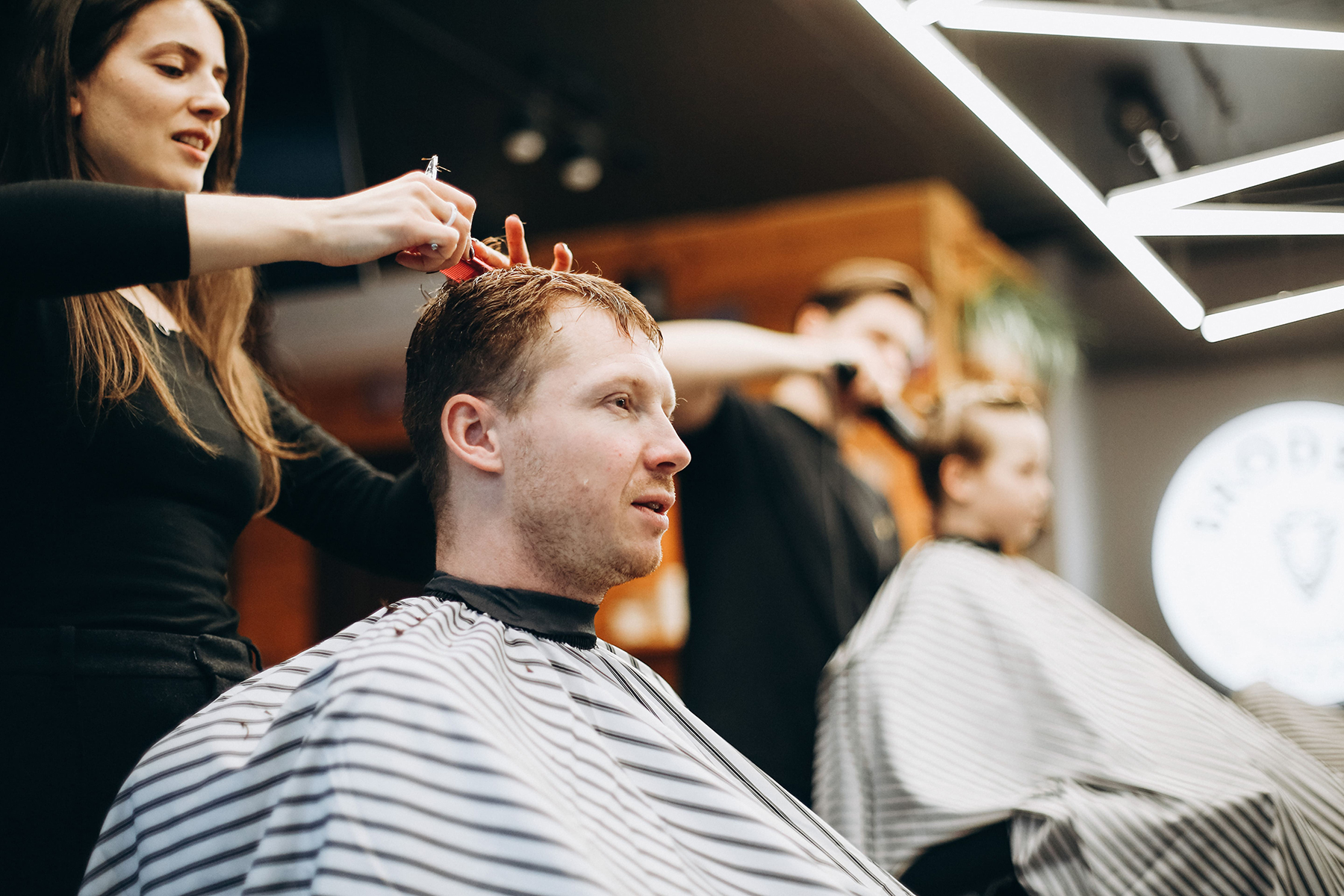Klasyczne strzyżenie męskie — BRODSKI Barbershop Warszawa Wilanów Profesjonalne klasyczne strzyżenie męskie w BRODSKI Barbershop Warszawa Wilanów — barber strzyże mężczyznę w fotelu fryzjerskim.