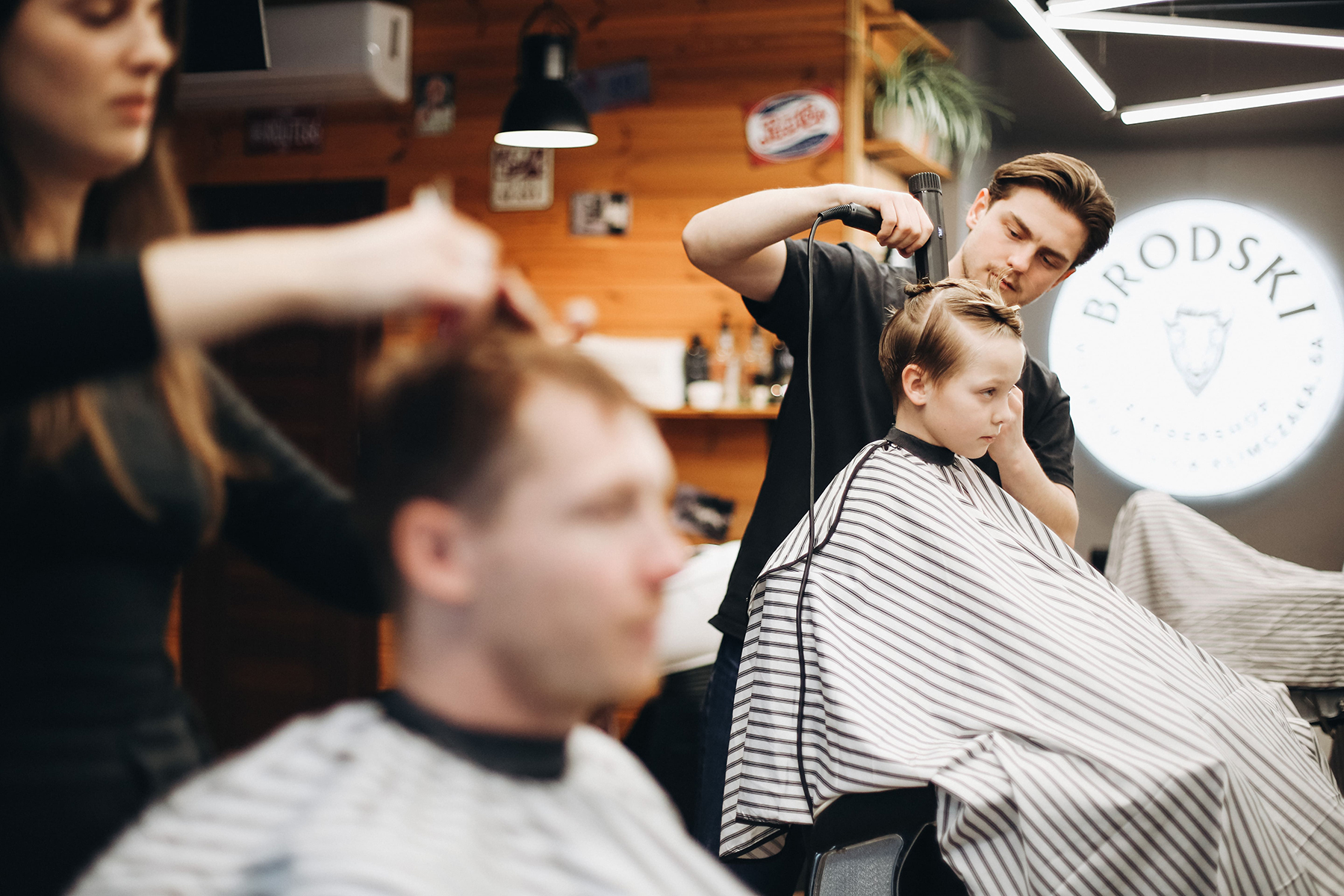 Ojciec i syn na sąsiadujących fotelach fryzjerskich w barbershopie BRODSKI w Wilanowie, Warszawa.
