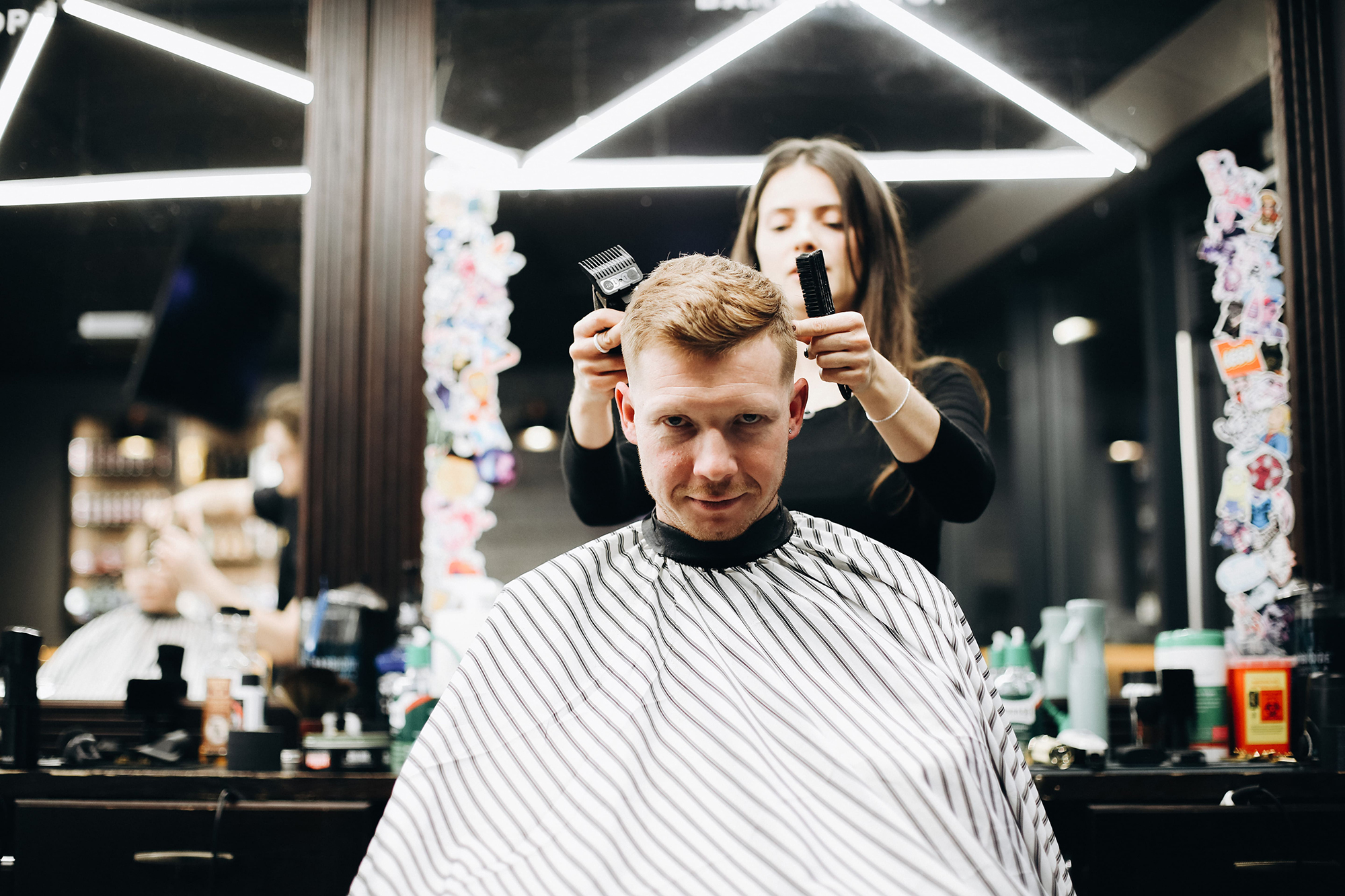 Proces klasycznego strzyżenia męskiego — BRODSKI Barbershop Barber w trakcie pracy nad klasycznym strzyżeniem męskim przy użyciu nożyczek i grzebienia w salonie BRODSKI Warszawa Wilanów.