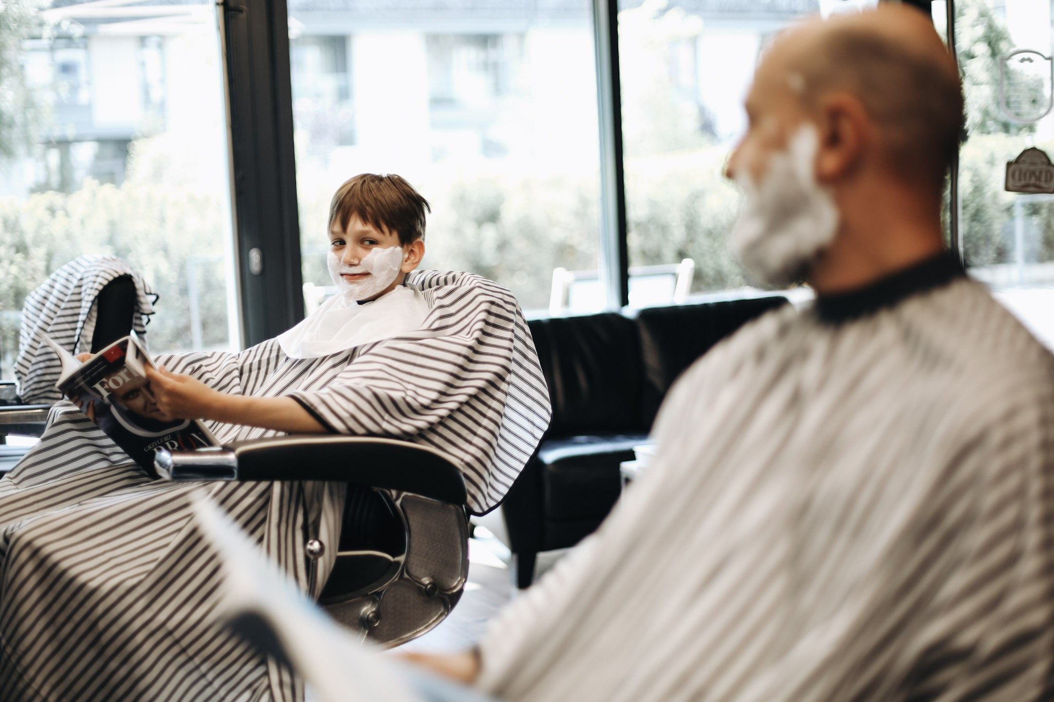 Ojciec i syn siedzą obok siebie na fotelach barberskich w BRODSKI Barbershop Wilanów, oboje z pianą na twarzy — pakiet Ojciec + Syn