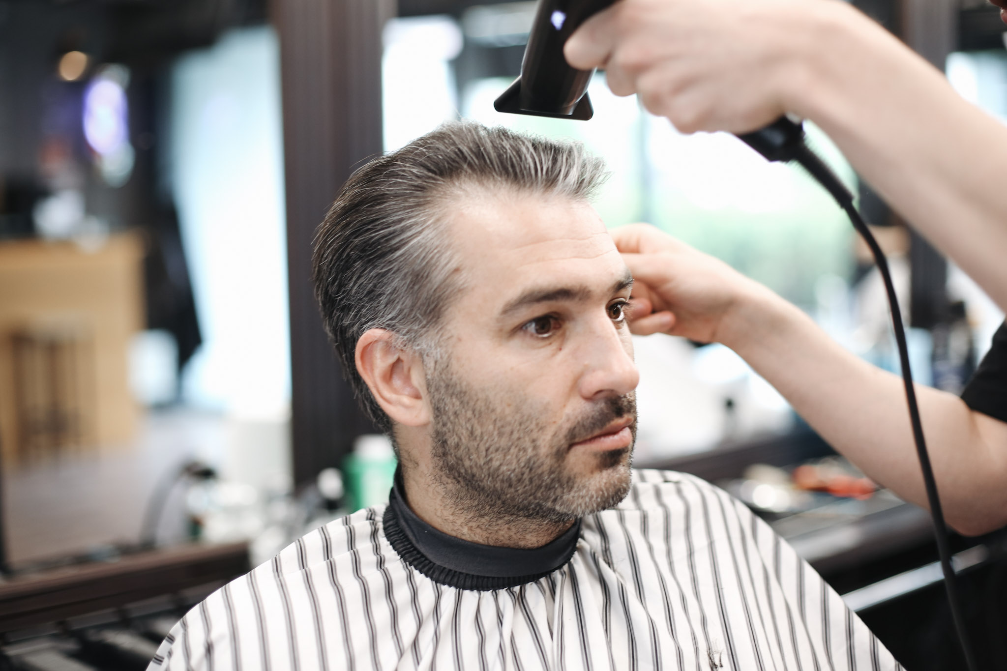 Barber suszy i układa włosy klienta fenem w BRODSKI Barbershop Wilanów