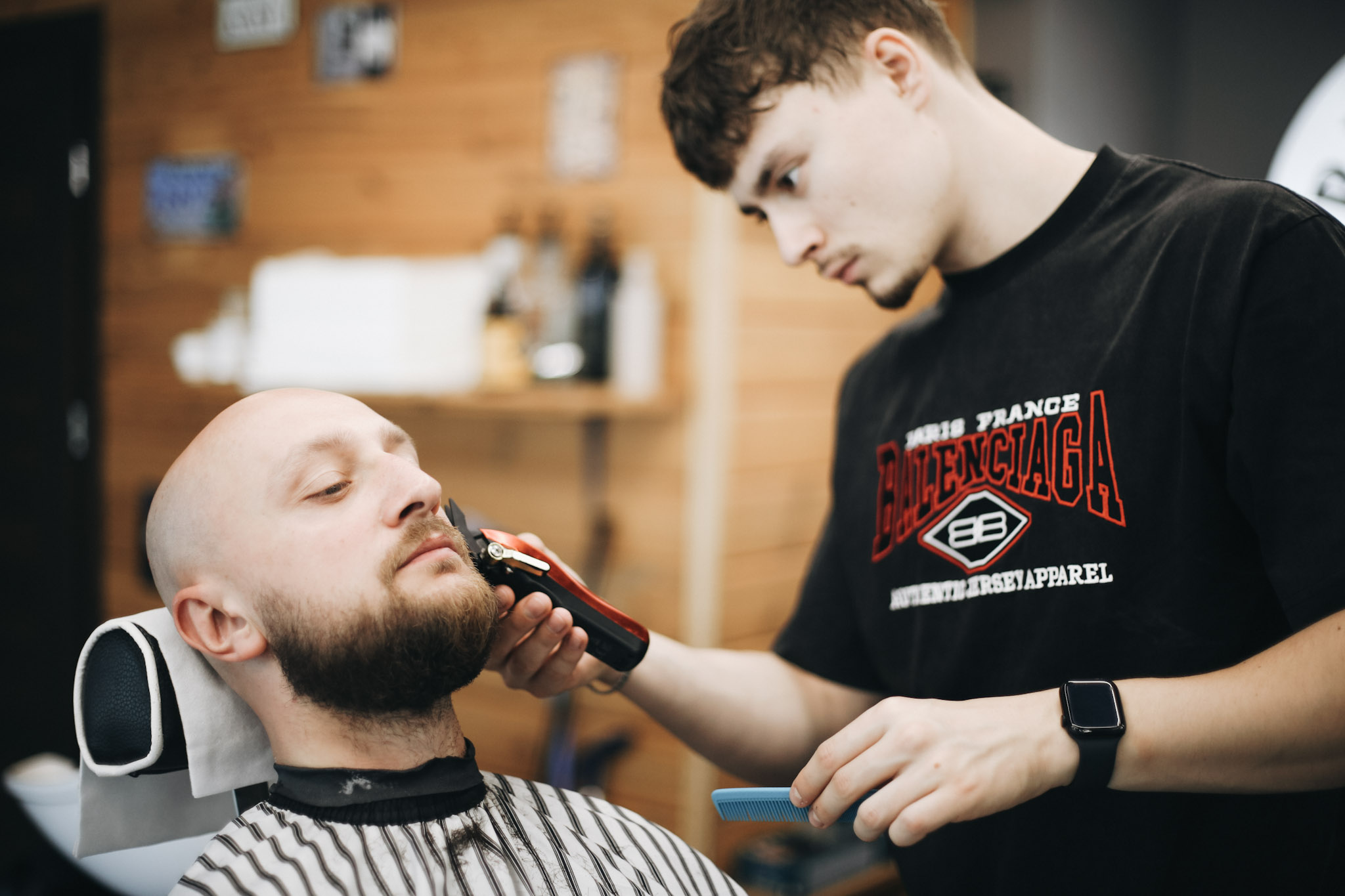 Barber stylizuje brodę maszynką u klienta z wygoloną głową w BRODSKI Barbershop Wilanów — konturowanie brody w pakiecie Łyse combo