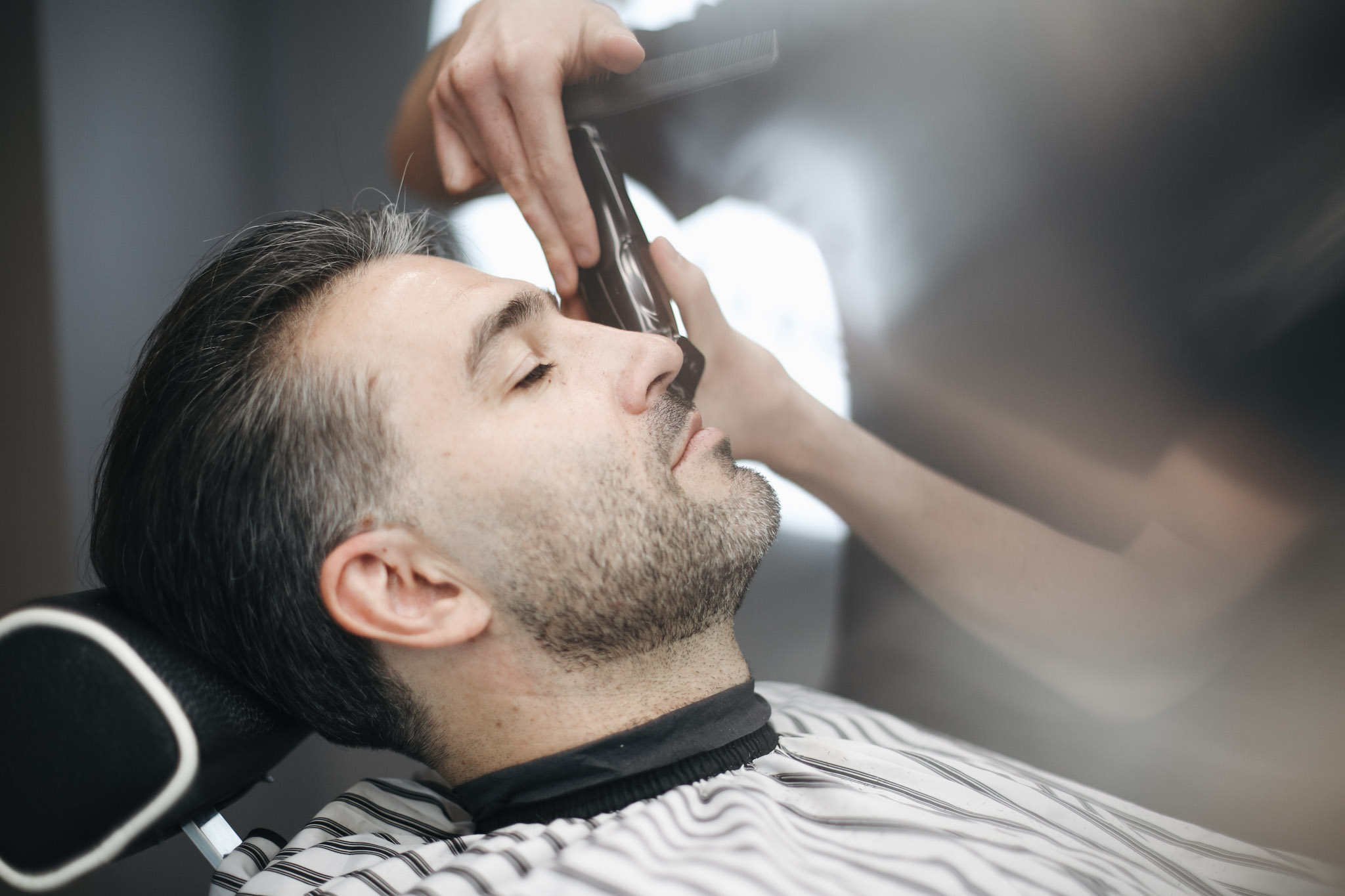 Professional barber trimming client's beard with precision razor at BRODSKI barbershop Wilanów