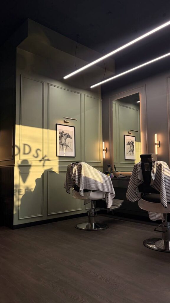Barber w Wilanowie naprzeciwko Auchan – fotel barberski w słońcu z cieniem logo BRODSKI na ścianie