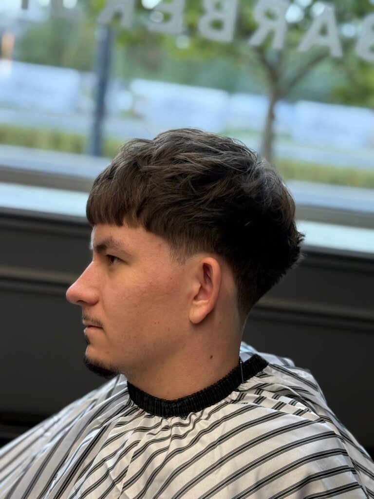 Textured crop with blunt fringe and mid taper, profile view, by barber Denis at BRODSKI Barbershop Wilanów, Warszawa